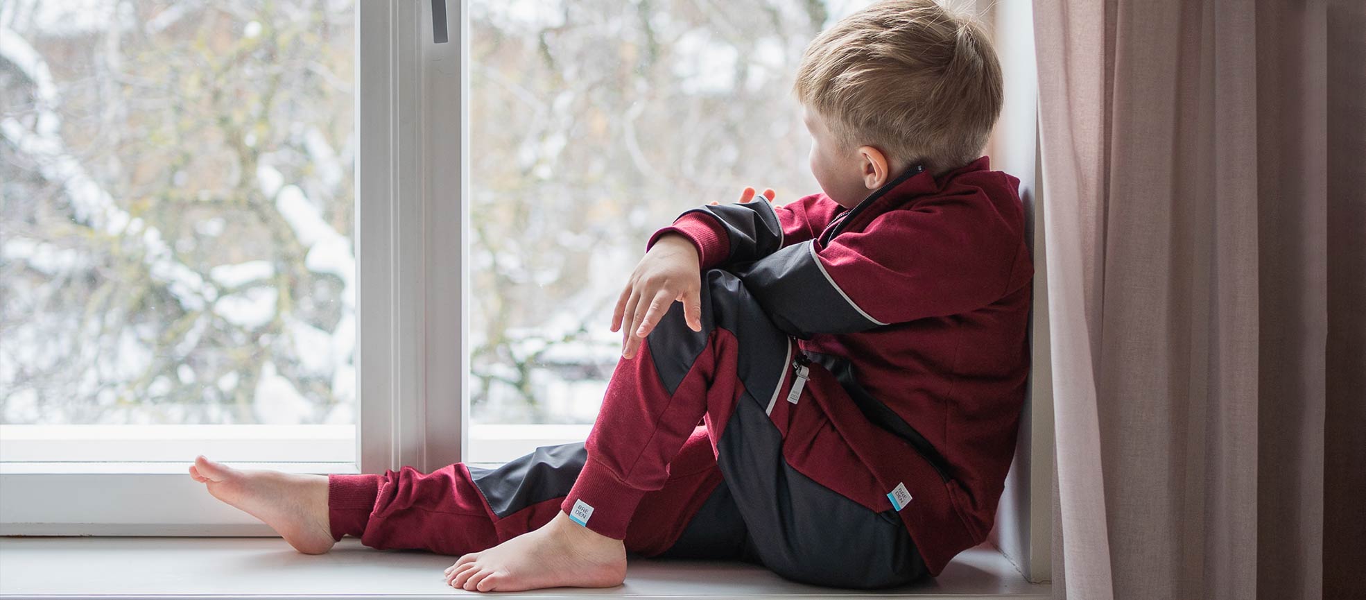 kid looking out of the window dreaming in organic cotton outdoor sweats