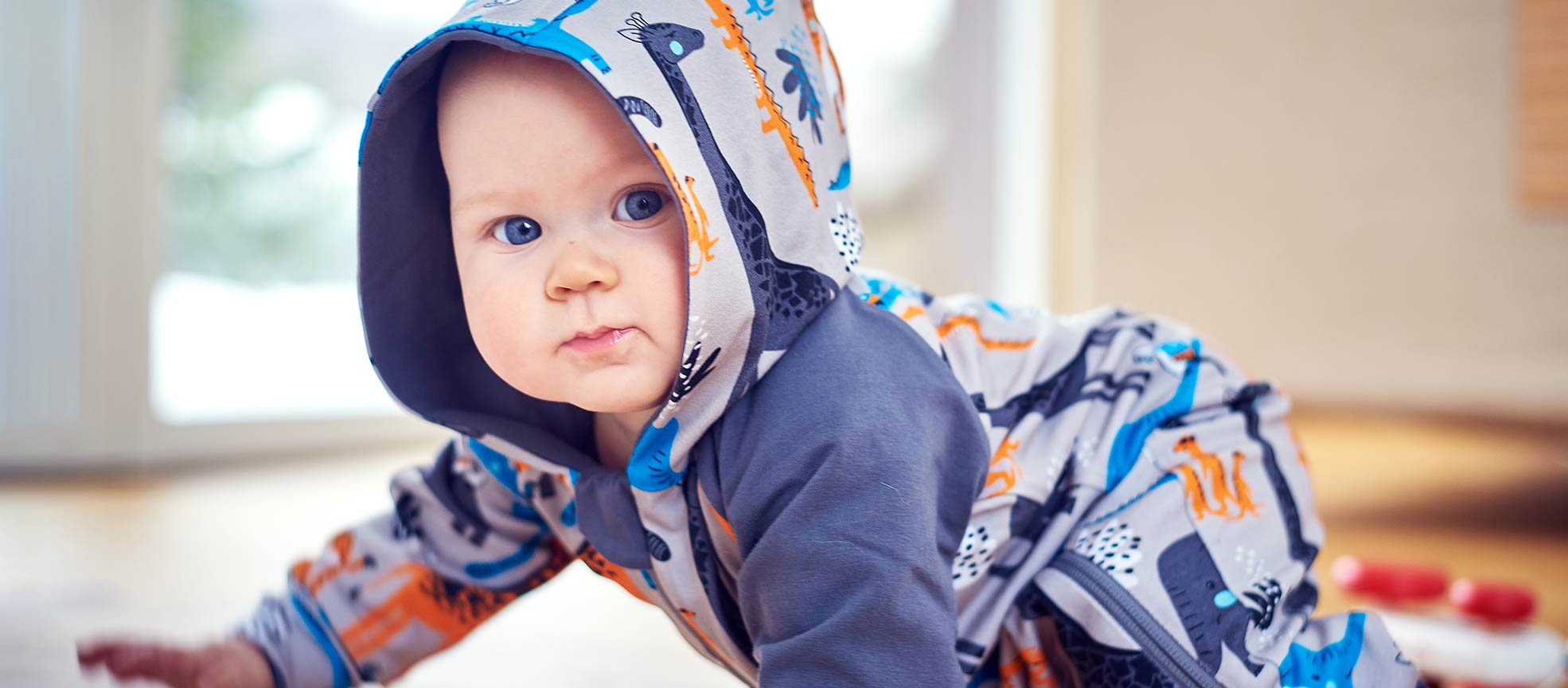 Baby crawling in comfy organic cotton jumpsuit with a hood